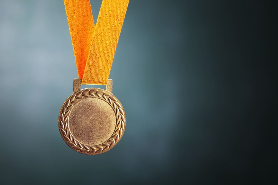 A gold medal hangs from an orange ribbon
