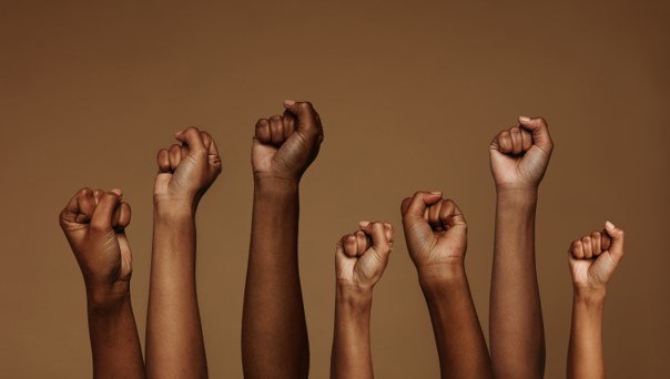 Ten black and brown hands posed in fists against a brown background