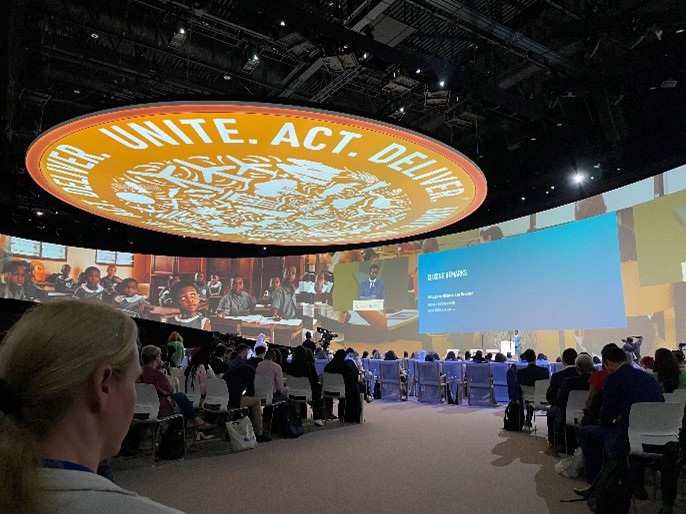 A large conference room with the words Unite. Act. Deliver.