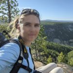 Kristin Kaser, a certified ecologist, posers over a scenic overlook in Yellowstone National Park