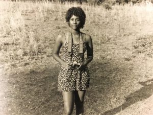 Young black woman outdoors - looking at the camera, and holding a camera