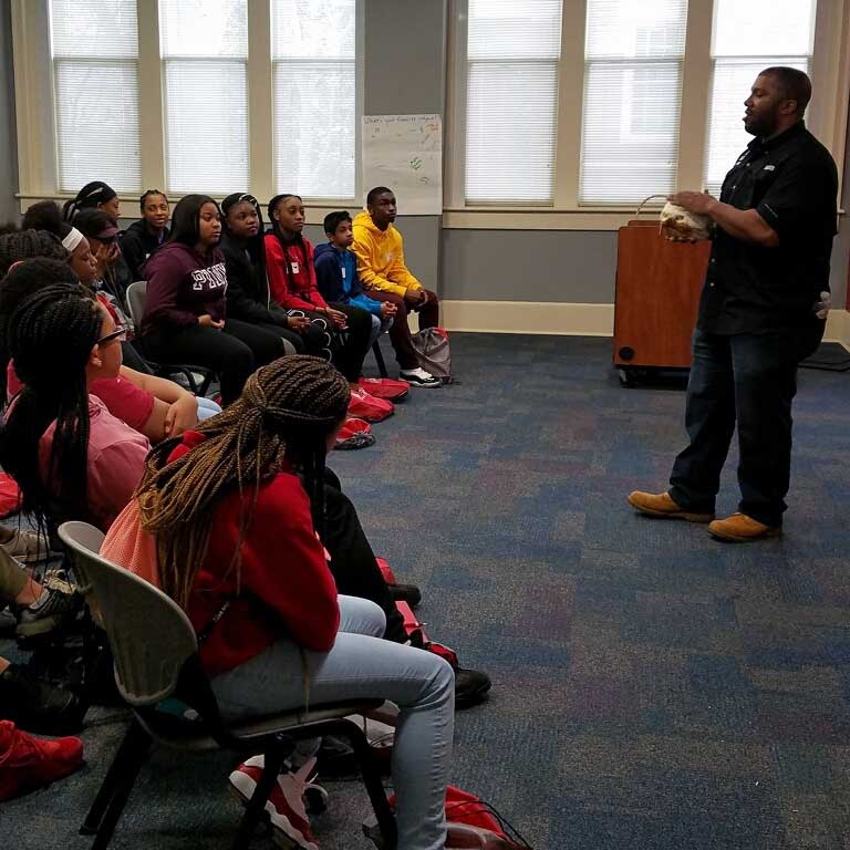 A black professor speaks before a group of black students.