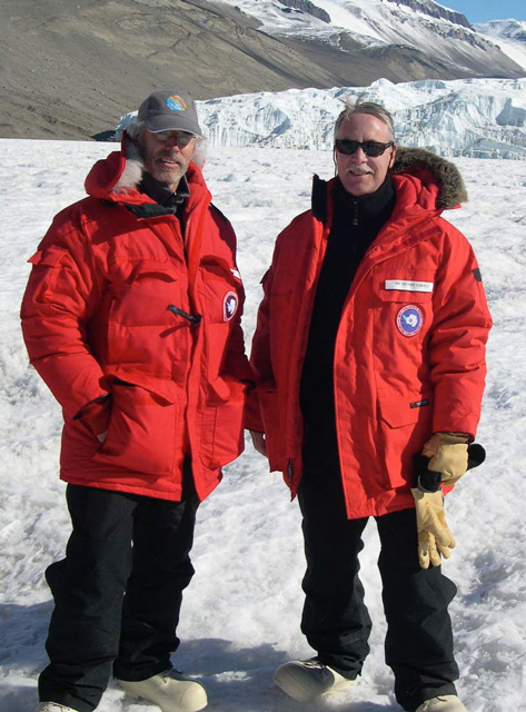 Philip Taylor and Henry Gholz stand in an artic landscape dressed in red winter coats.