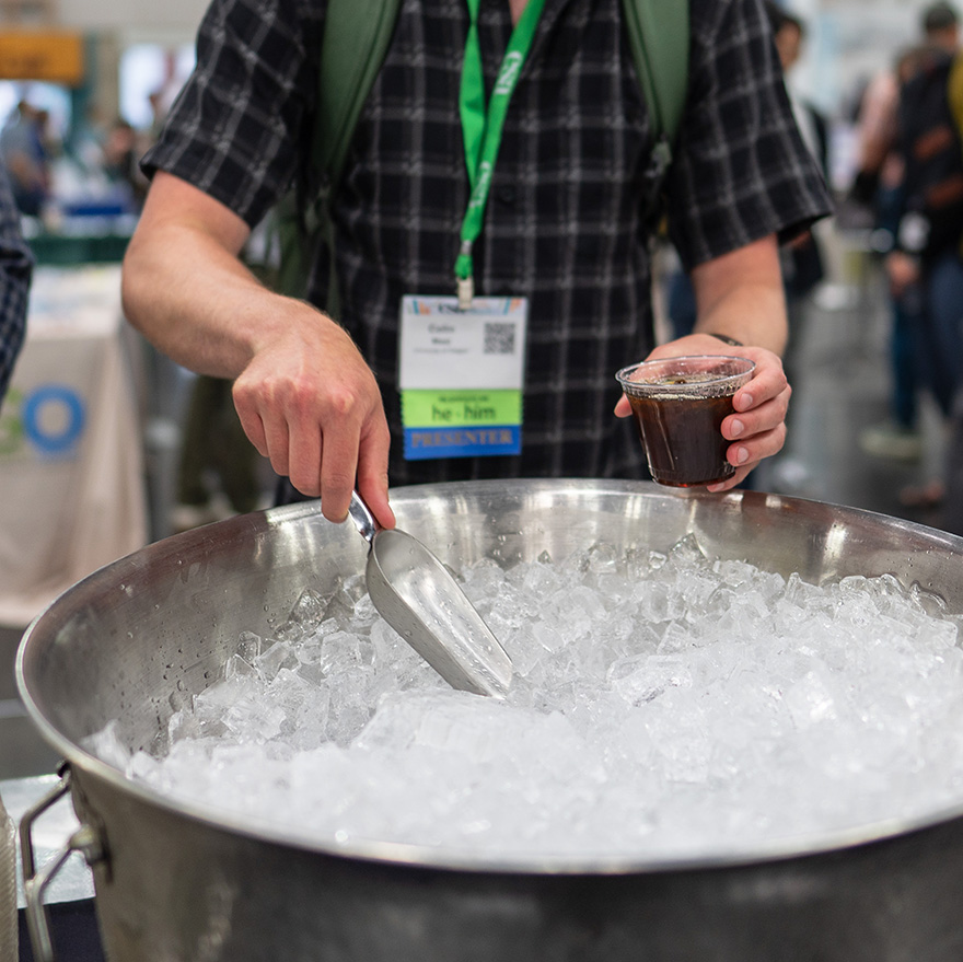 A conference goer scoops ice for their beverage. 