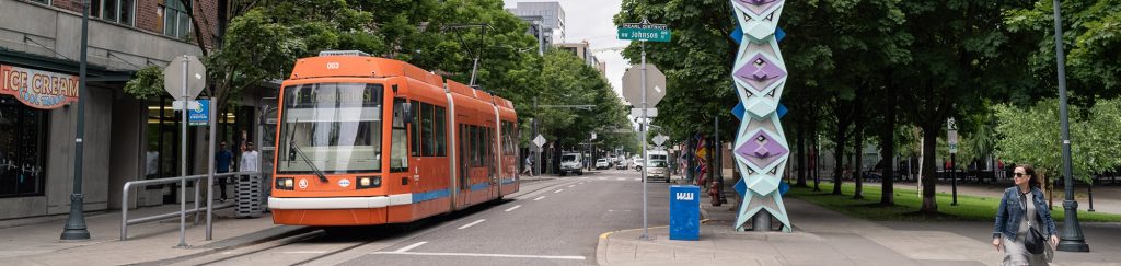 An orange street car stopped prepares to cross an intersection.