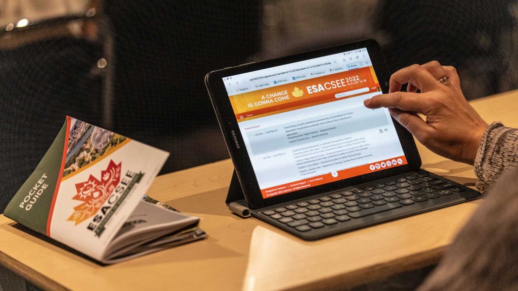 An attendee explores the annual meeting program application online and with a copy of the paper bound program next to her.