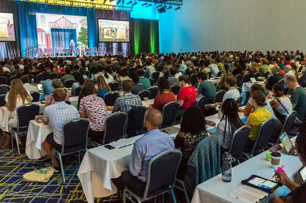A presenter from the 2019 annual meeting presents before a full auditorium.