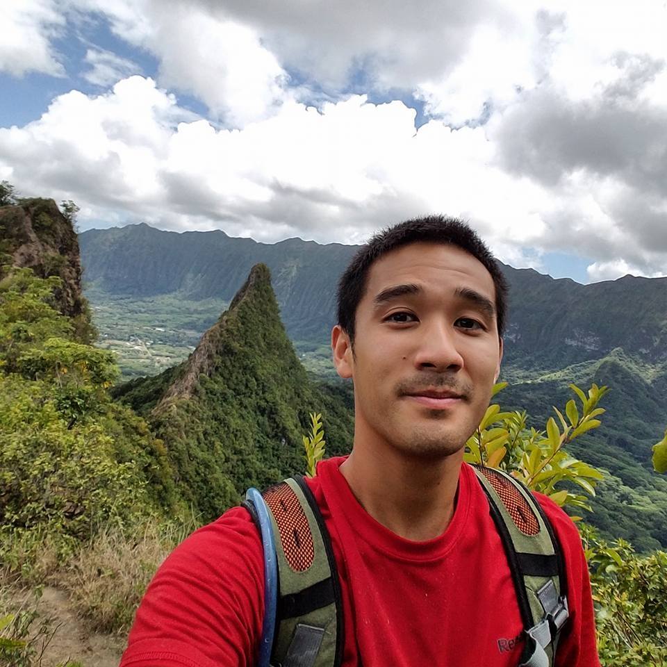 A selfie in front of a green covered mountain range.