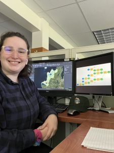 SIP intern sits in front of two computer screens showing maps and model