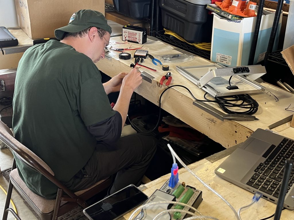 Person wiring a station inside while sitting at a desk.