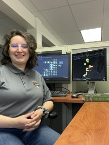 Meagan (author), in a grey polo, sitting in front of two computer monitors. One monitoring displaying a GIS model. The second Monitoring displaying a map of SLBE symbolized red to yellow to green. 