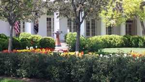 The president's podium with flowers in the foreground and trees overhead.