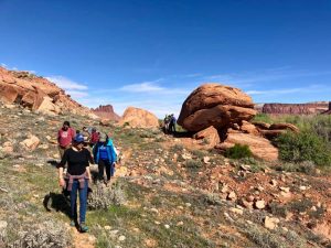 Students walk a rock trail in an arid landscape.